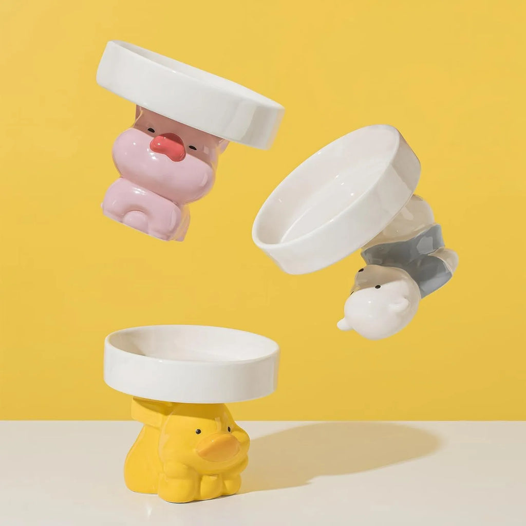 Raised ceramic cat bowl with cute animal design in pink, yellow, or white on a white background