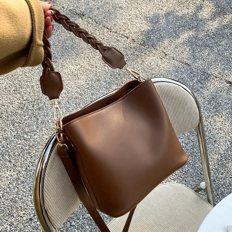 Khaki PU woven one-shoulder crossbody bucket bag with retro design on a mannequin