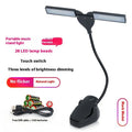 Black rechargeable LED music stand lamp with clip, shown illuminating sheet music.