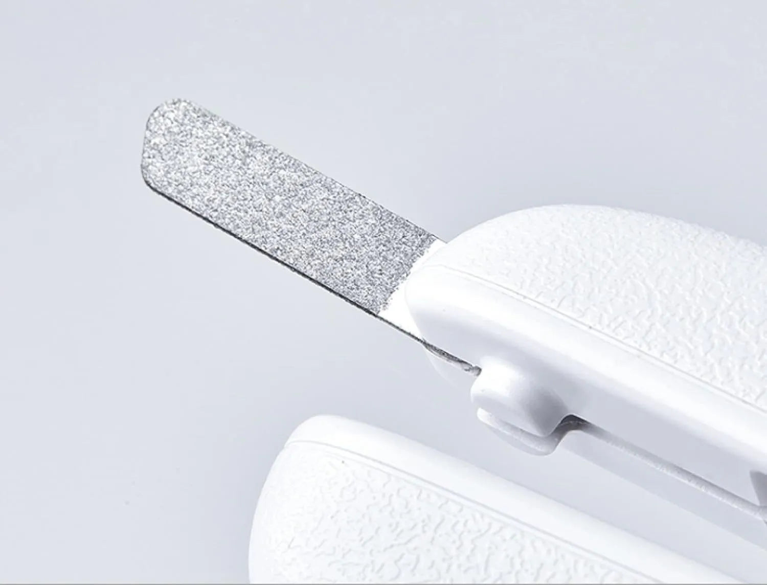 White pet nail clippers with LED light, transparent guard, and leather-like handle next to a nail file.