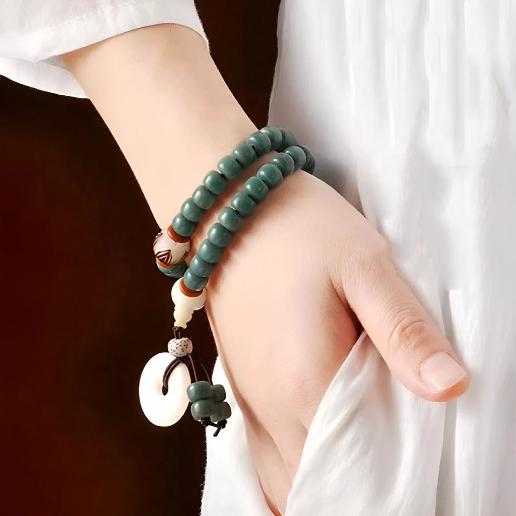 White and green beaded bracelet with a double ring safety buckle and a prominent double ring lotus bead decoration.