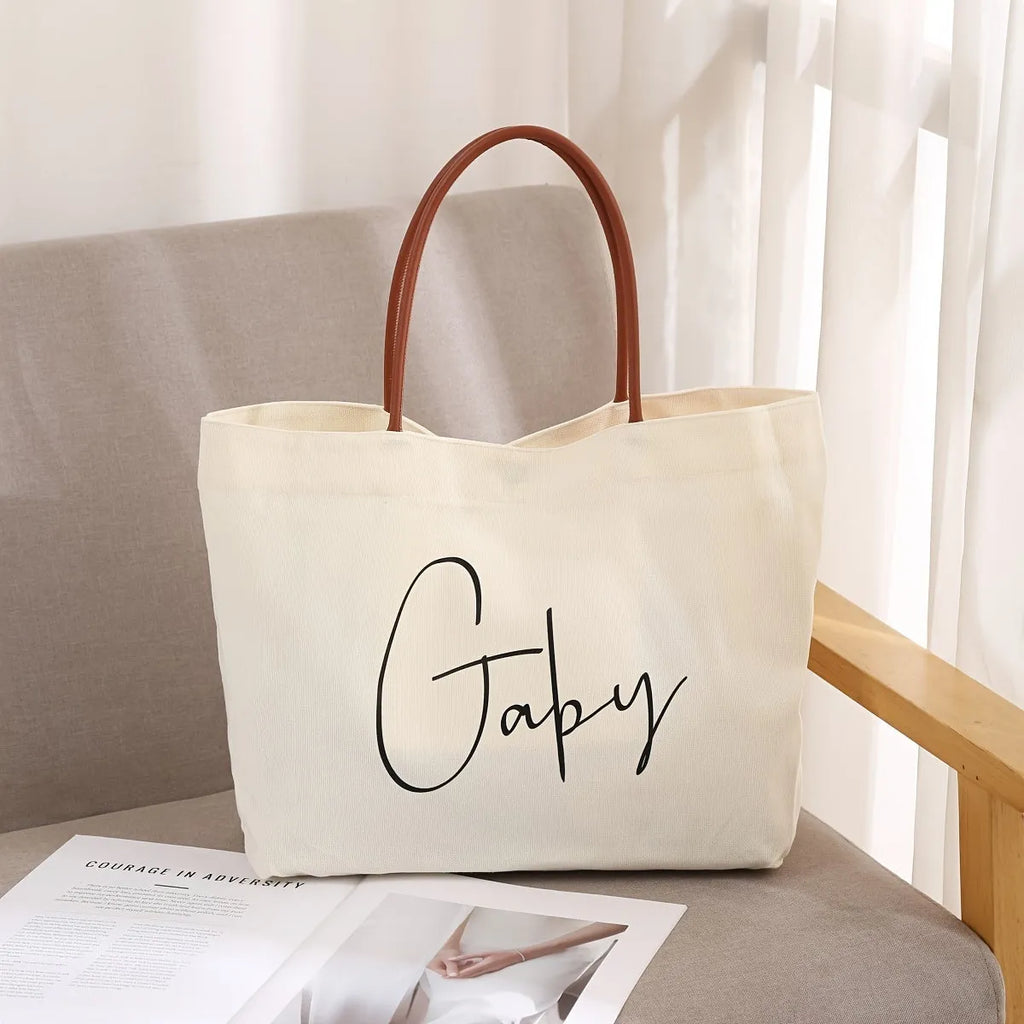 Beige white canvas tote bag with adjustable cotton handles showing reinforced bottom stitching.