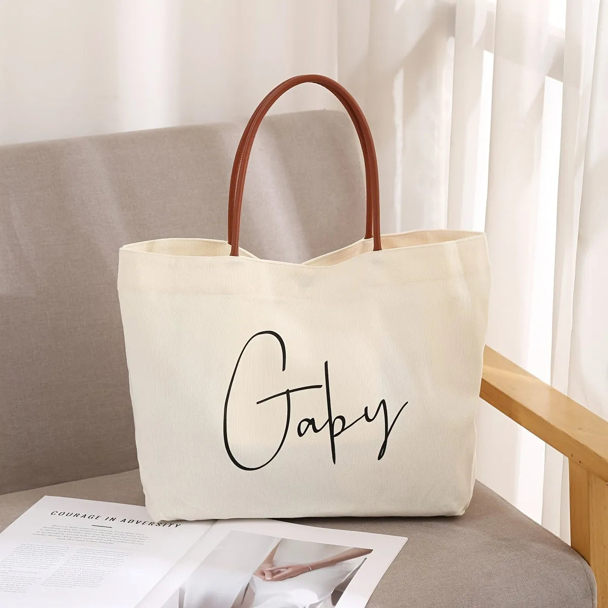 Beige white canvas tote bag with adjustable cotton handles showing reinforced bottom stitching.