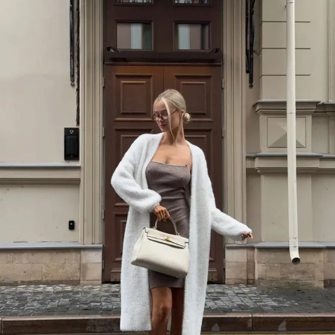 White thick knitted women's cardigan jacket with long sleeves and extended length.