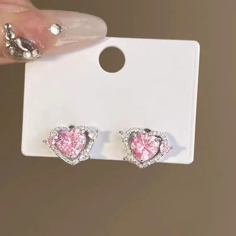 White gold colour heart-shaped stud earrings for women on a jewellery card.