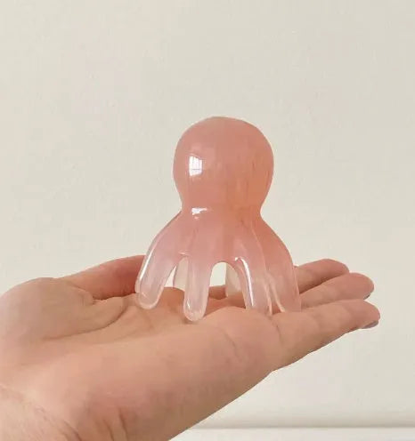 Pink octopus-shaped facial massage comb with dual-pronged tip for periocular pressure points