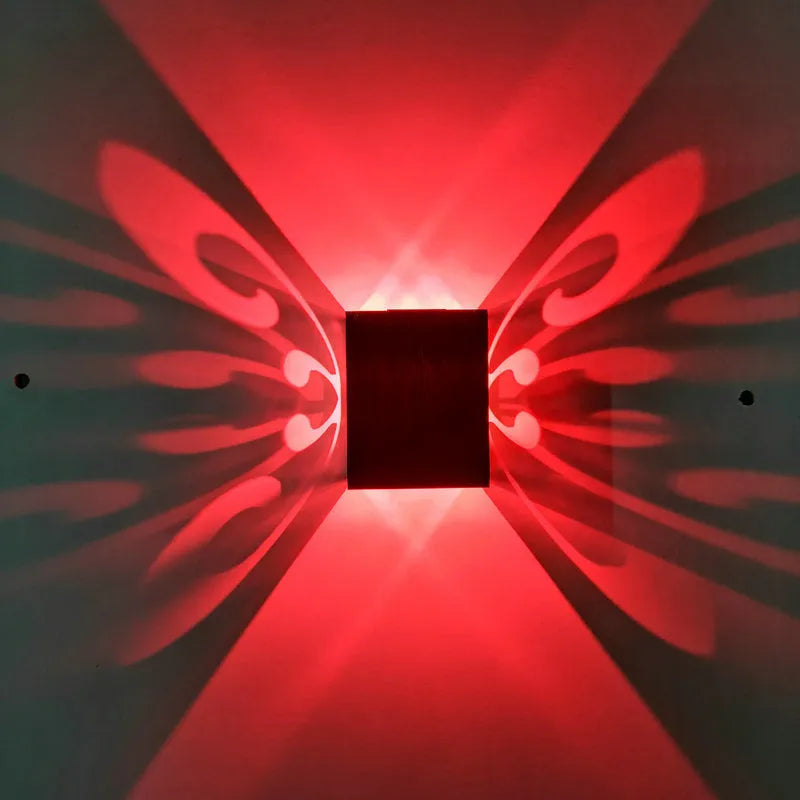 Modern aluminium butterfly-shaped LED wall lamp with remote control on a plain background.