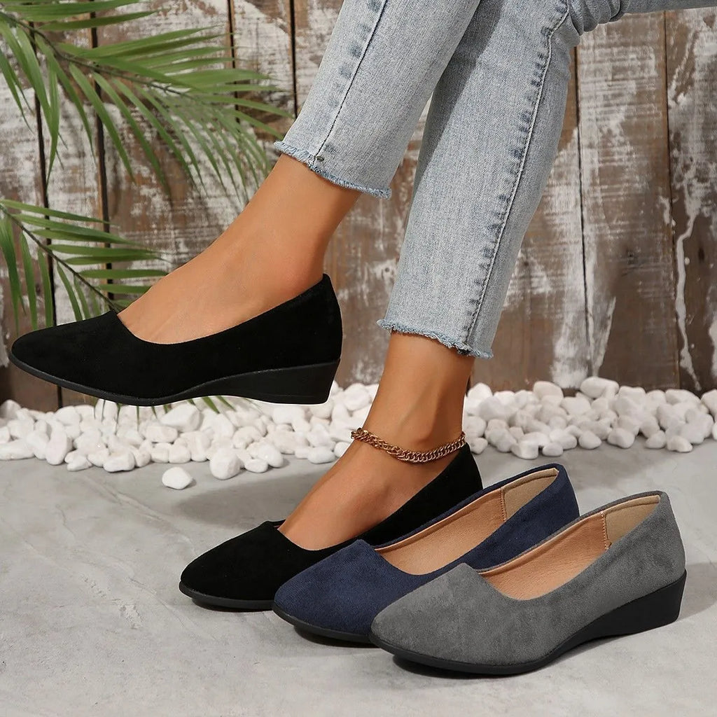 Women's black suede wedge pumps with pointed toe and low rubber sole.