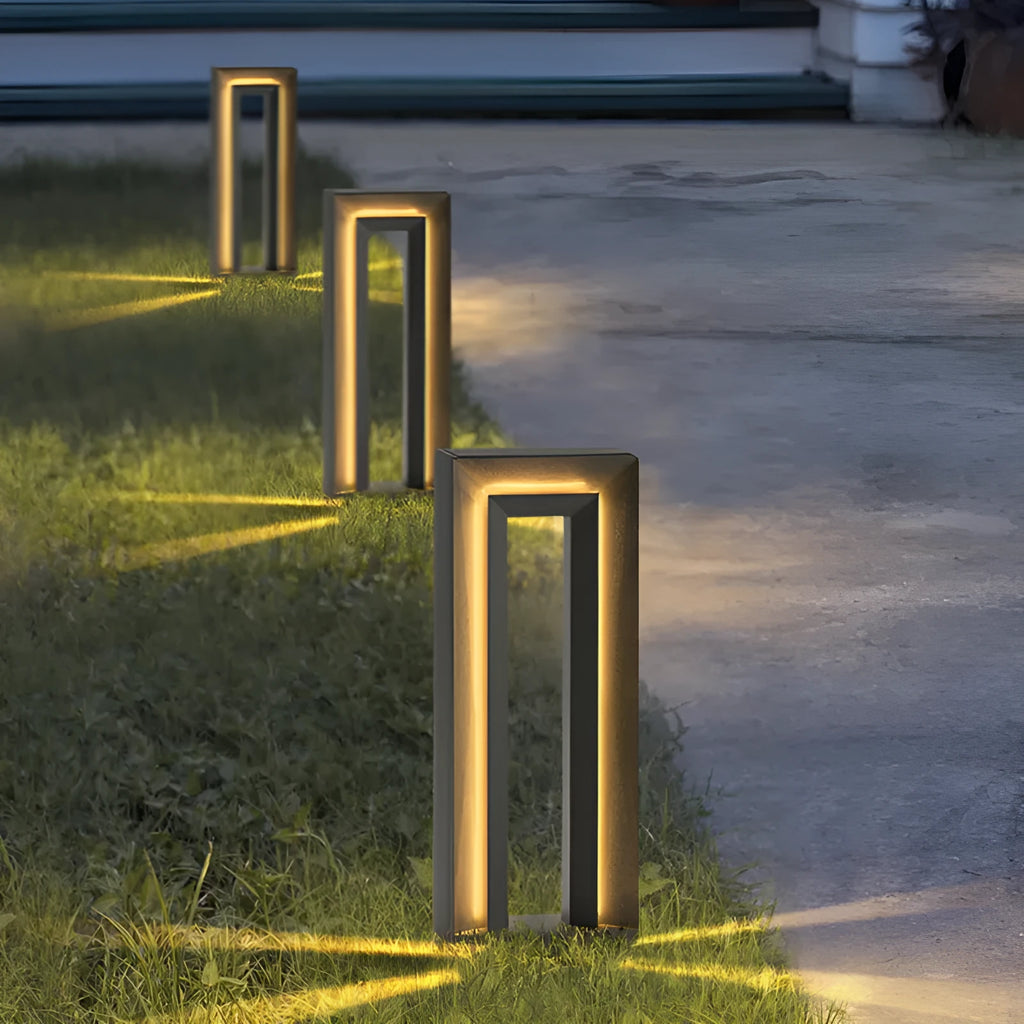 Modern square stainless steel outdoor garden lamp with geometric design on a patio.