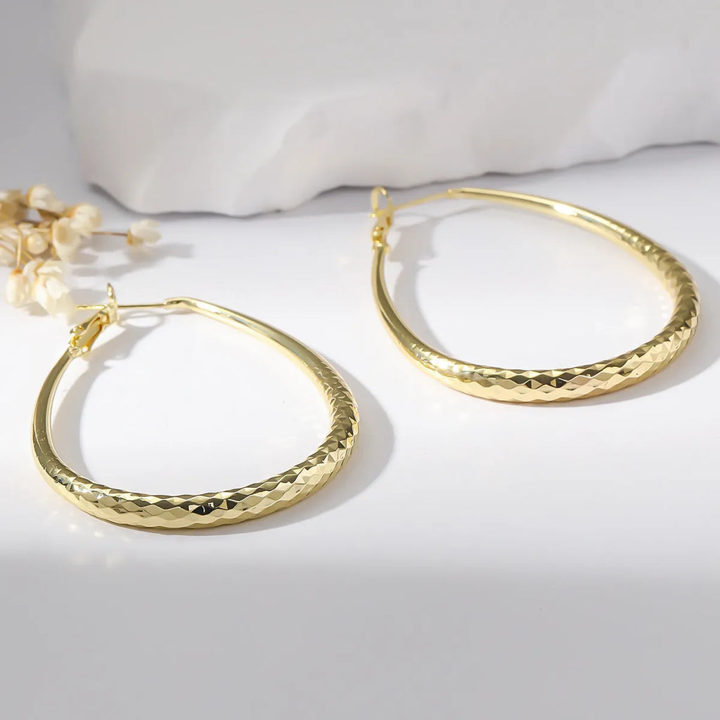 Gold egg-shaped copper earrings with hypoallergenic posts and spring fasteners, unisex geometric ellipse design