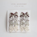 Set of eight children's cloth bow hair clips in various colours including beige polka dot, pink, blue floral, and wine red plaid patterns.