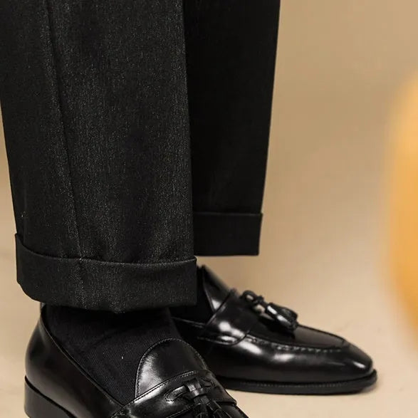 Men's black leather tassel loafers with rubber sole shown from side view