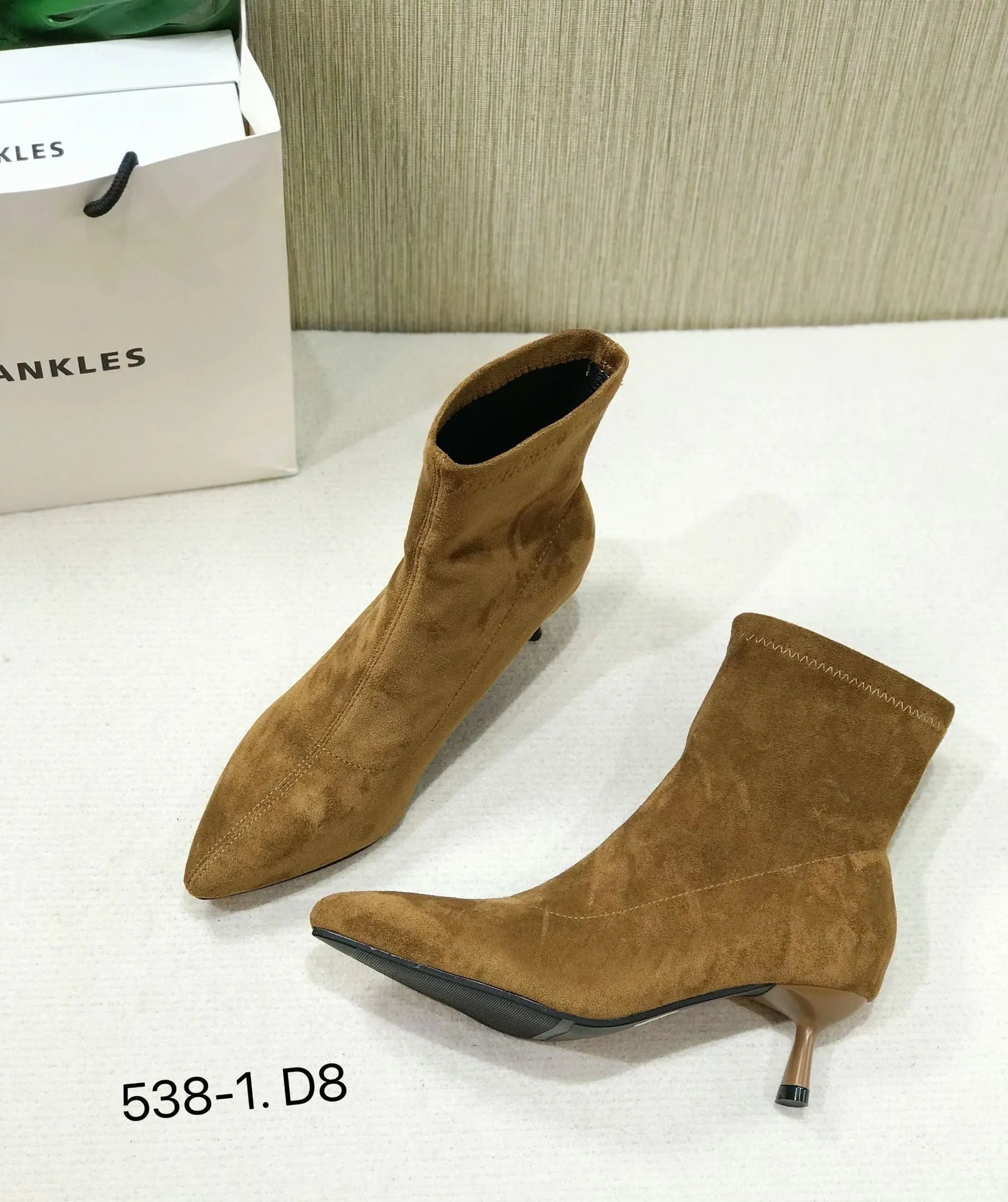 Black pointed toe women's ankle boots with a stiletto heel on a plain background
