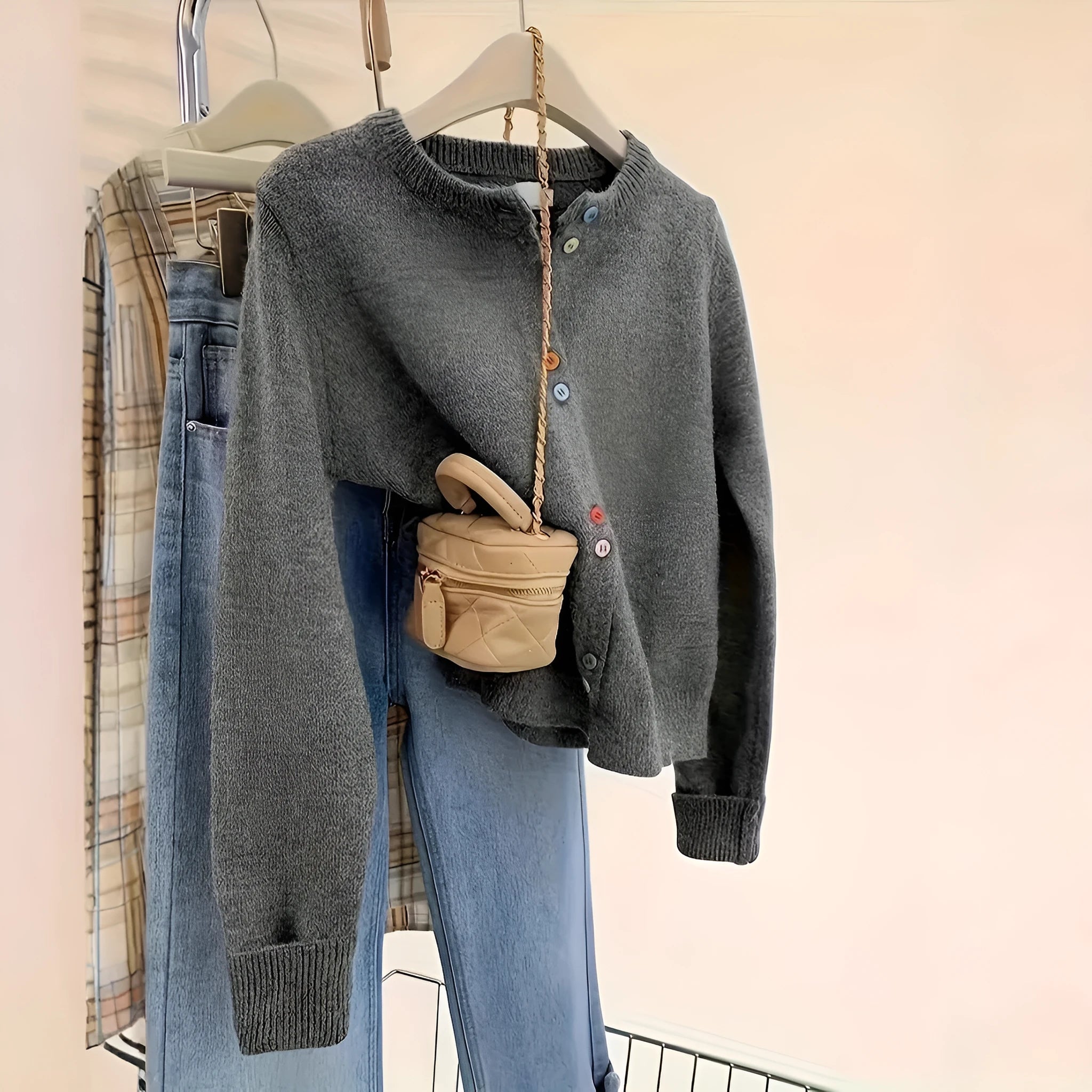 Dark grey women's button-front cardigan sweater with long sleeves on a hanger.