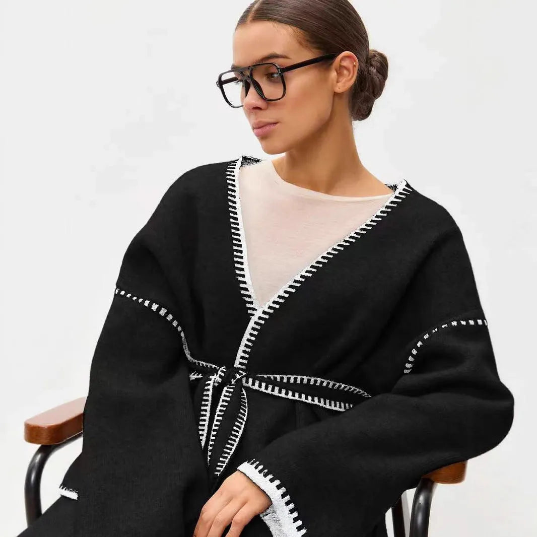 Loose mid-length knitted cardigan sweater coat with a lace-up front, shown in a neutral colour.