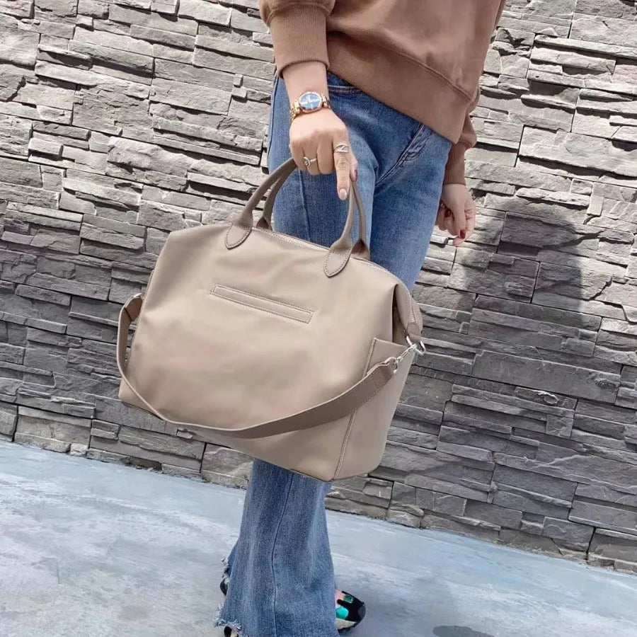 Waterproof nylon shoulder bag with leather trims in black or light khaki colour, showing 35cm dimensions