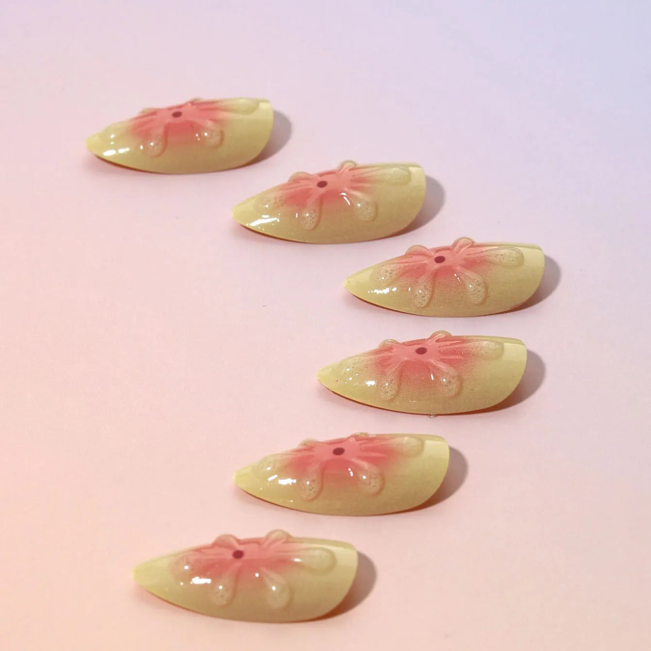 Simple fake nails set with pink and white 3D cartoon flower designs on detachable plastic armour pieces.