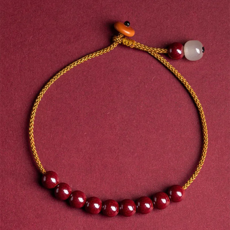 Close-up of a geometric design bracelet made from dark red cinnabar and Hetian jade on a wrist.