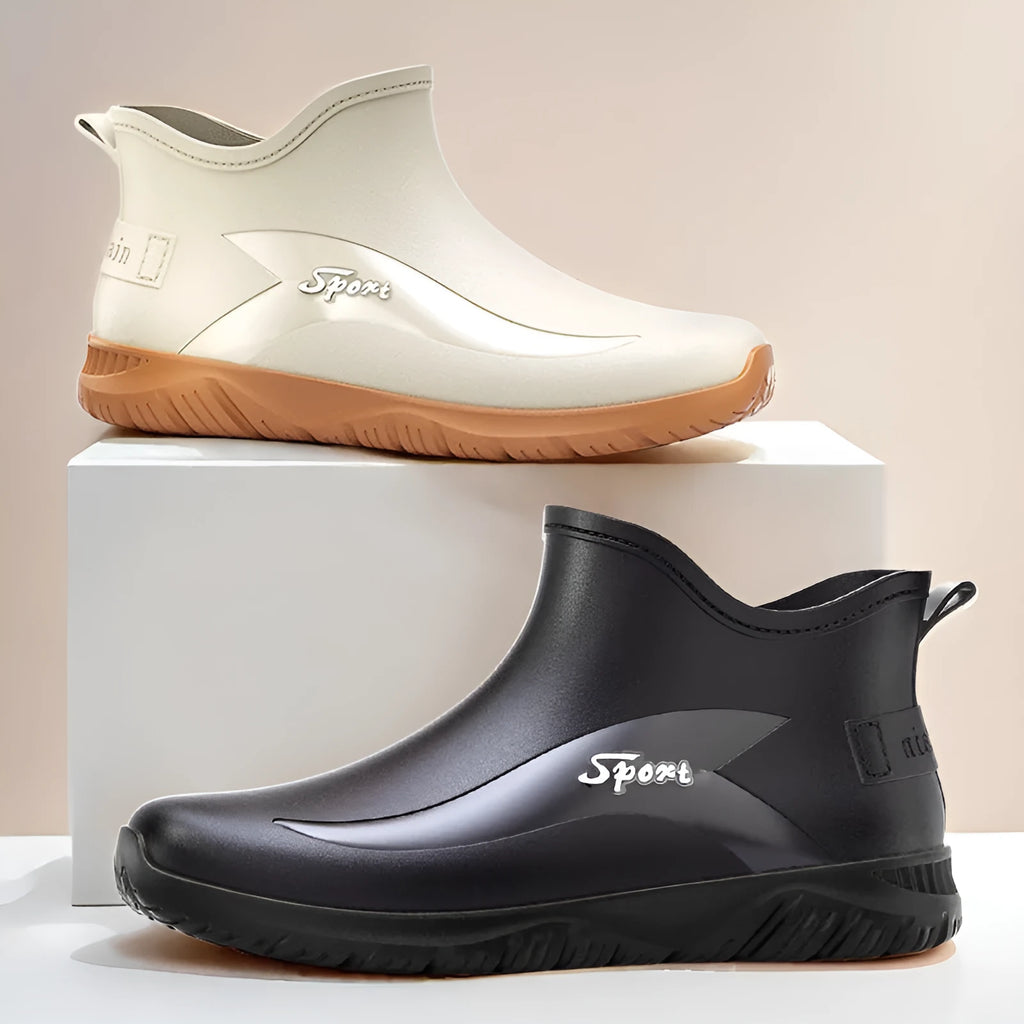 Men's short ankle-height rubber boots in black with non-slip flat soles on a wet surface