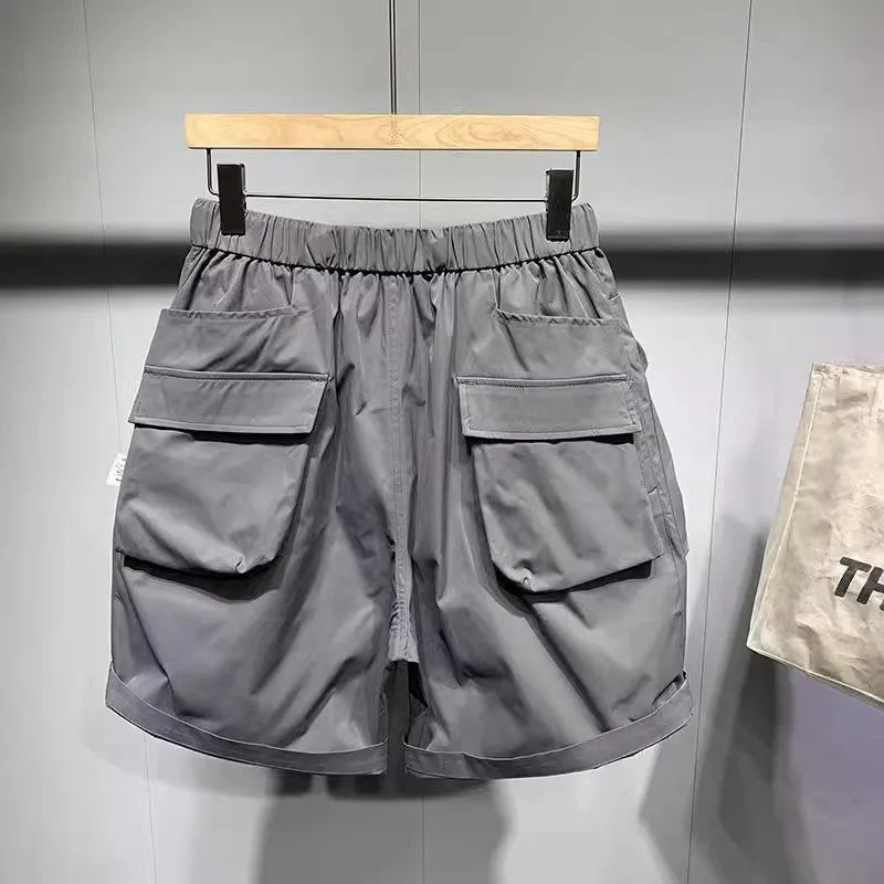 Men's loose fit grey workwear shorts with pockets, shown above the knee.