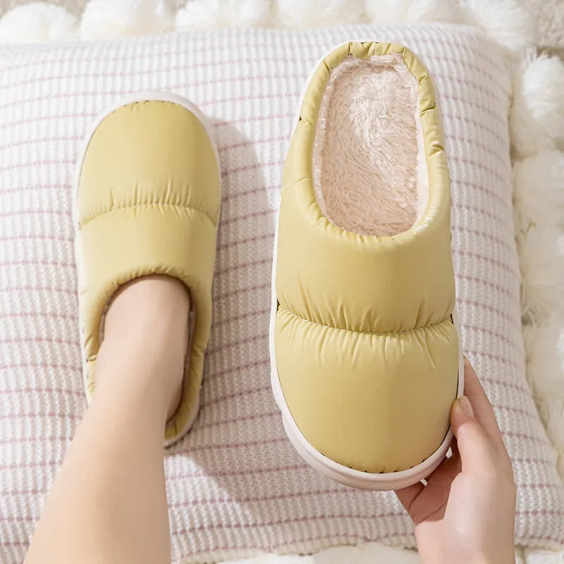 Blue down cotton slippers with artificial leather upper, thick rubber sole, and plush lining shown on a wooden floor.