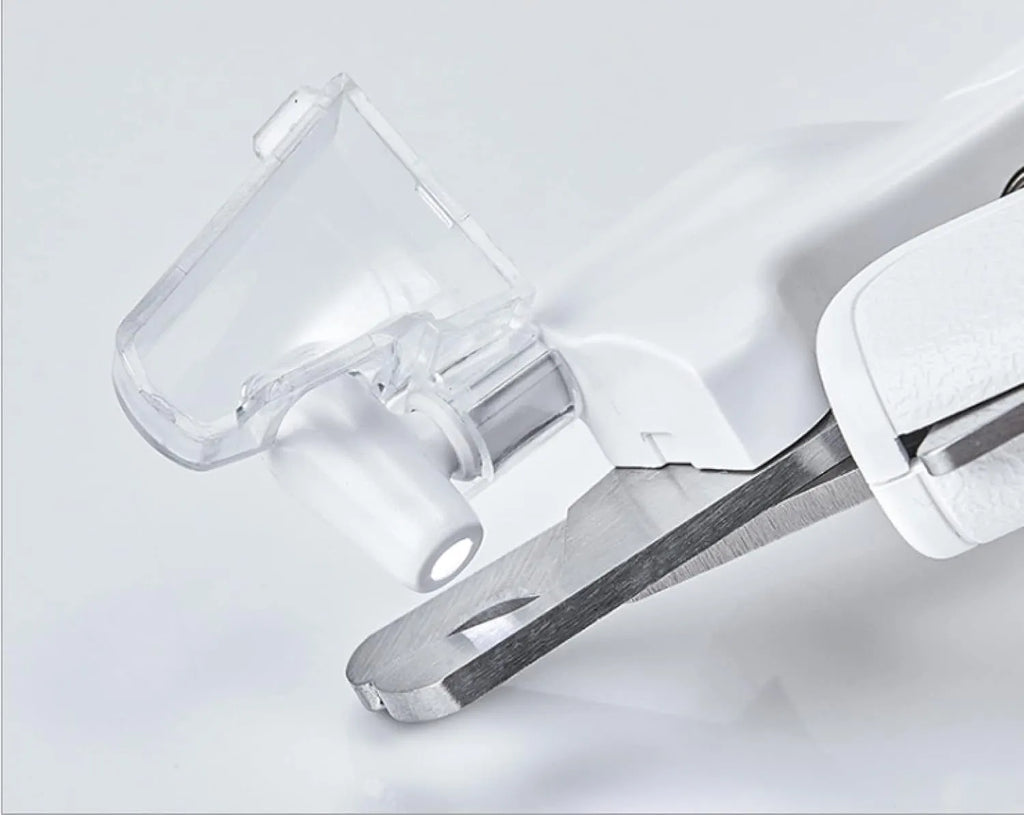 White pet nail clippers with LED light, transparent guard, and leather-like handle next to a nail file.