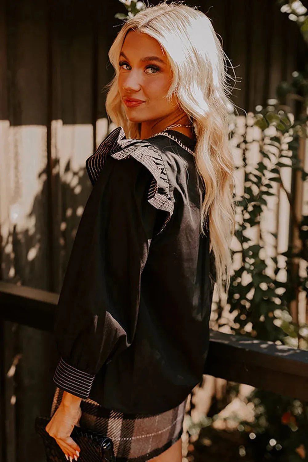 Black long sleeve V-neck blouse for women featuring ruffle details and visible contrast stitching on the seams.
