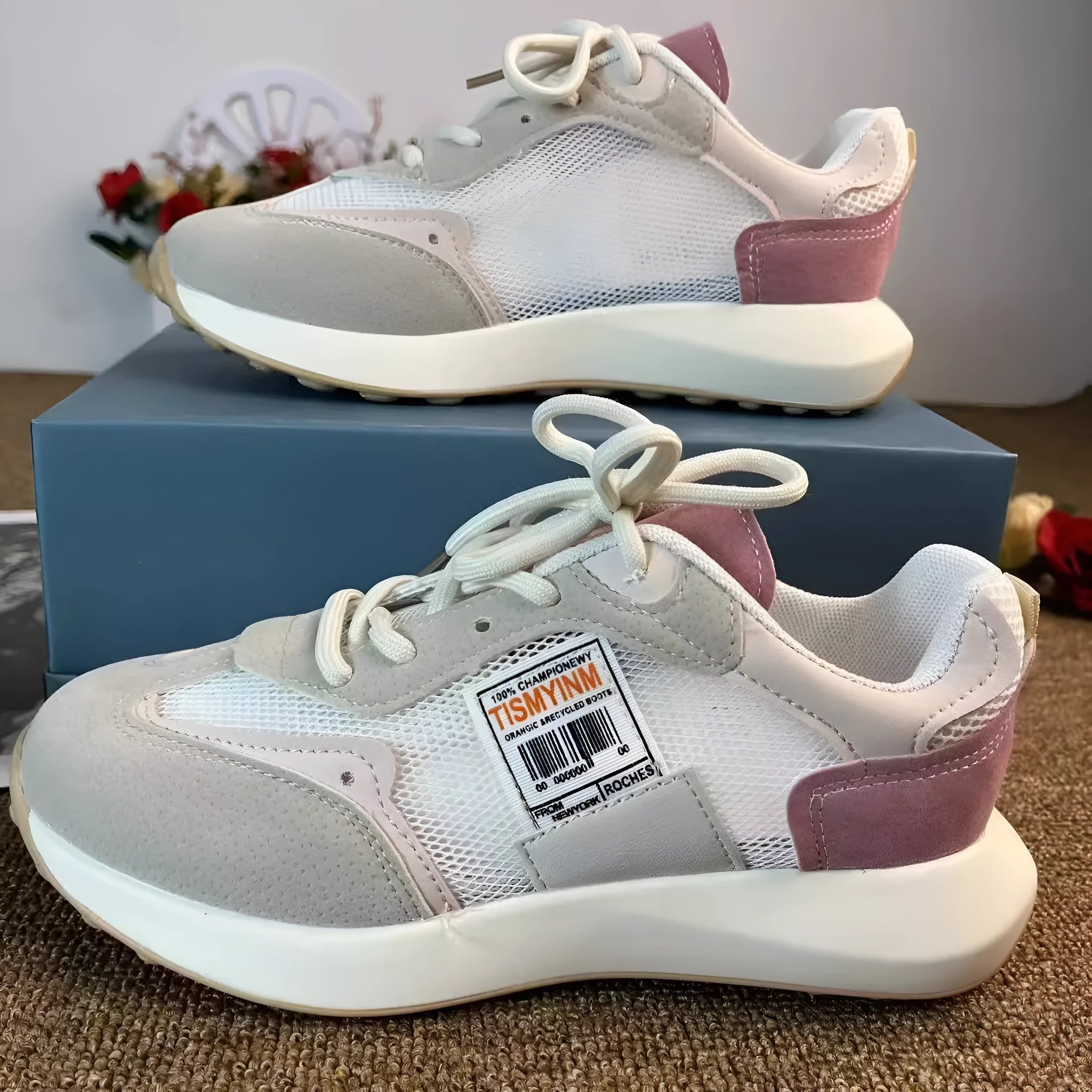 Grey and pink women's low-top retro sneaker with round toe and rubber sole on a white background.