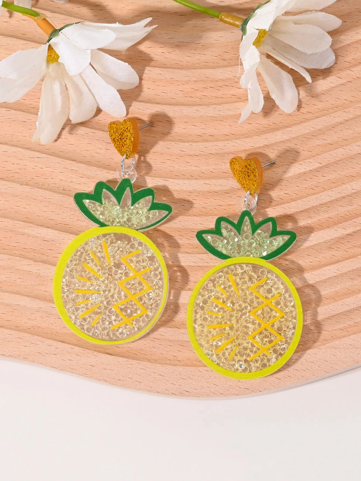 A pair of colourful acrylic earrings with a cake design next to other fruit and ice cream style earrings.