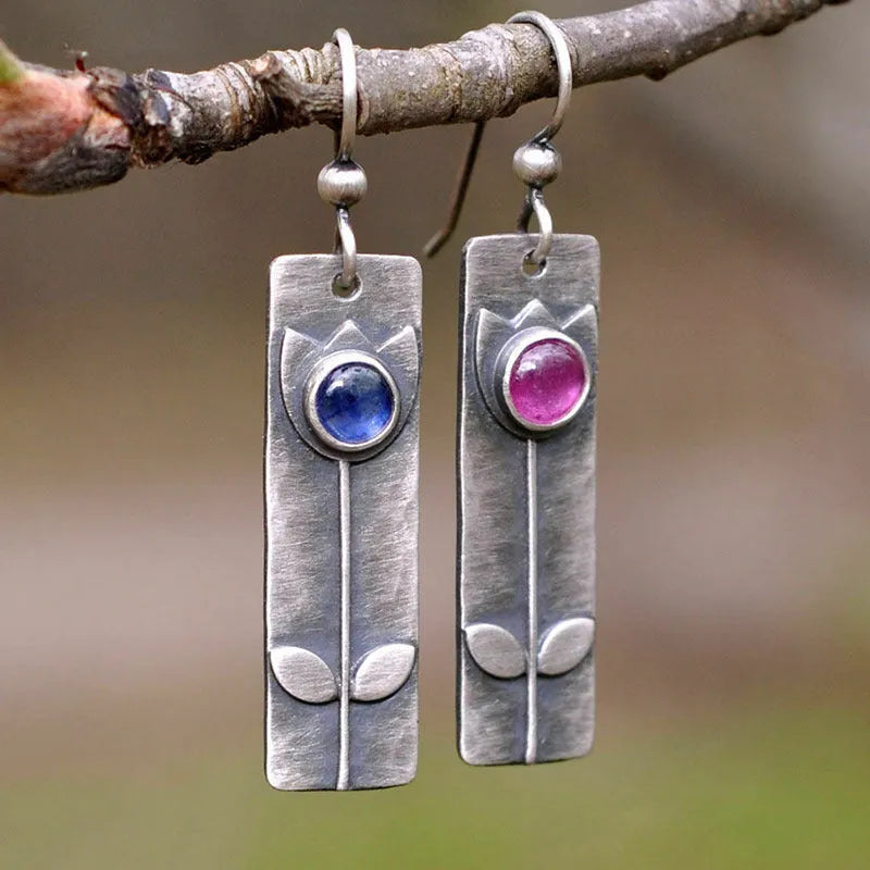 Antique finish red sapphire earrings with elliptical gemstones in a geometric design.