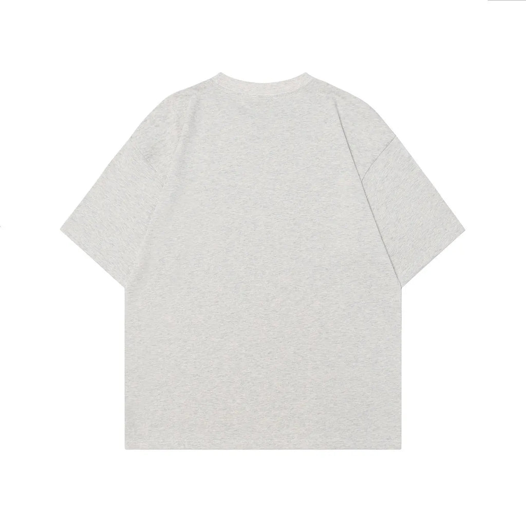 Man wearing a grey loose-fit cotton T-shirt with a retro character design print on the front.