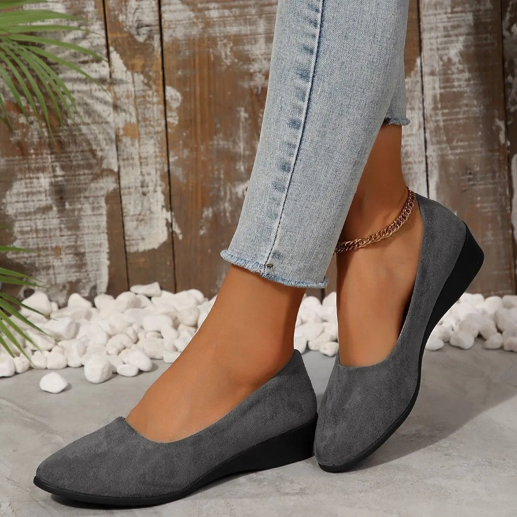 Women's black suede wedge pumps with pointed toe and low rubber sole.