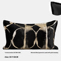 Black and gold abstract pattern decorative flannel pillow with removable cover on a grey sofa.
