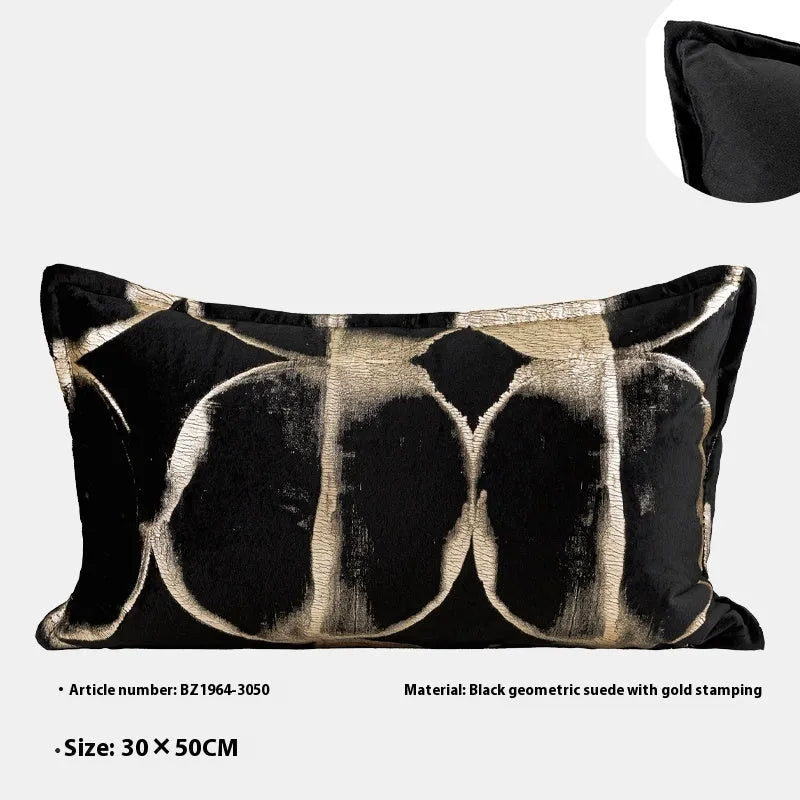 Black and gold abstract pattern decorative flannel pillow with removable cover on a grey sofa.