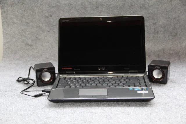 Small black square USB-powered computer speaker with audio and USB cables