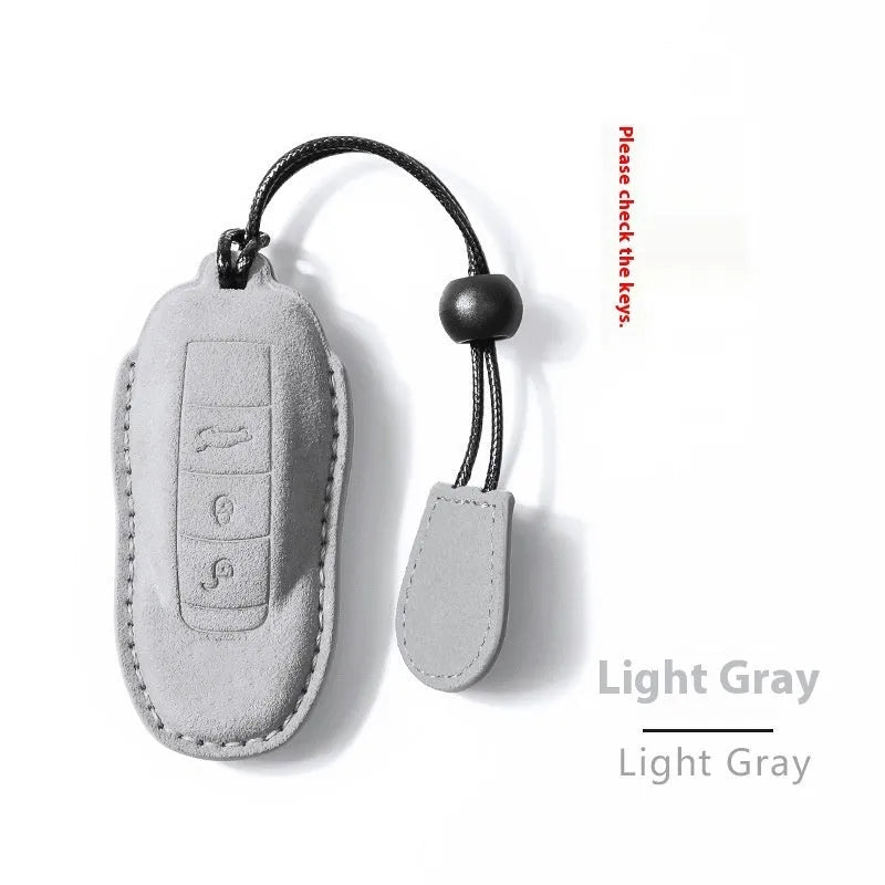 Suede car key cover in cement grey, dark green, light grey, and orange colour options