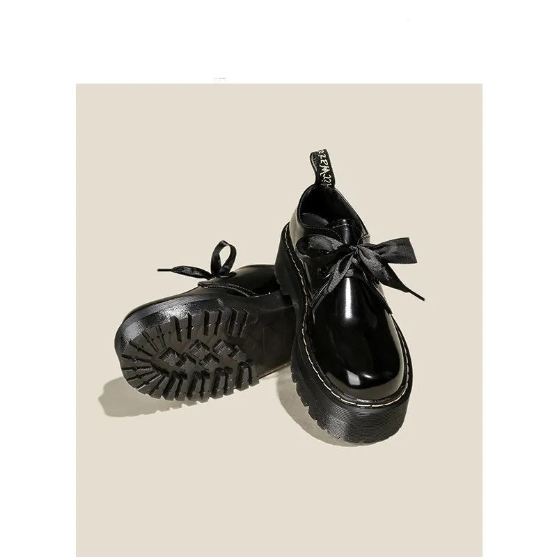 Women's black thick-soled leather shoes with cross-strap closure and ribbon detailing
