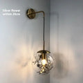 Modern glass wall lamp with metallic finish mounted beside bed for bedside lighting