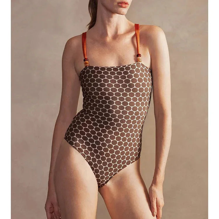 Women's blue dot print one-piece swimsuit with a matching wrap skirt laid flat.