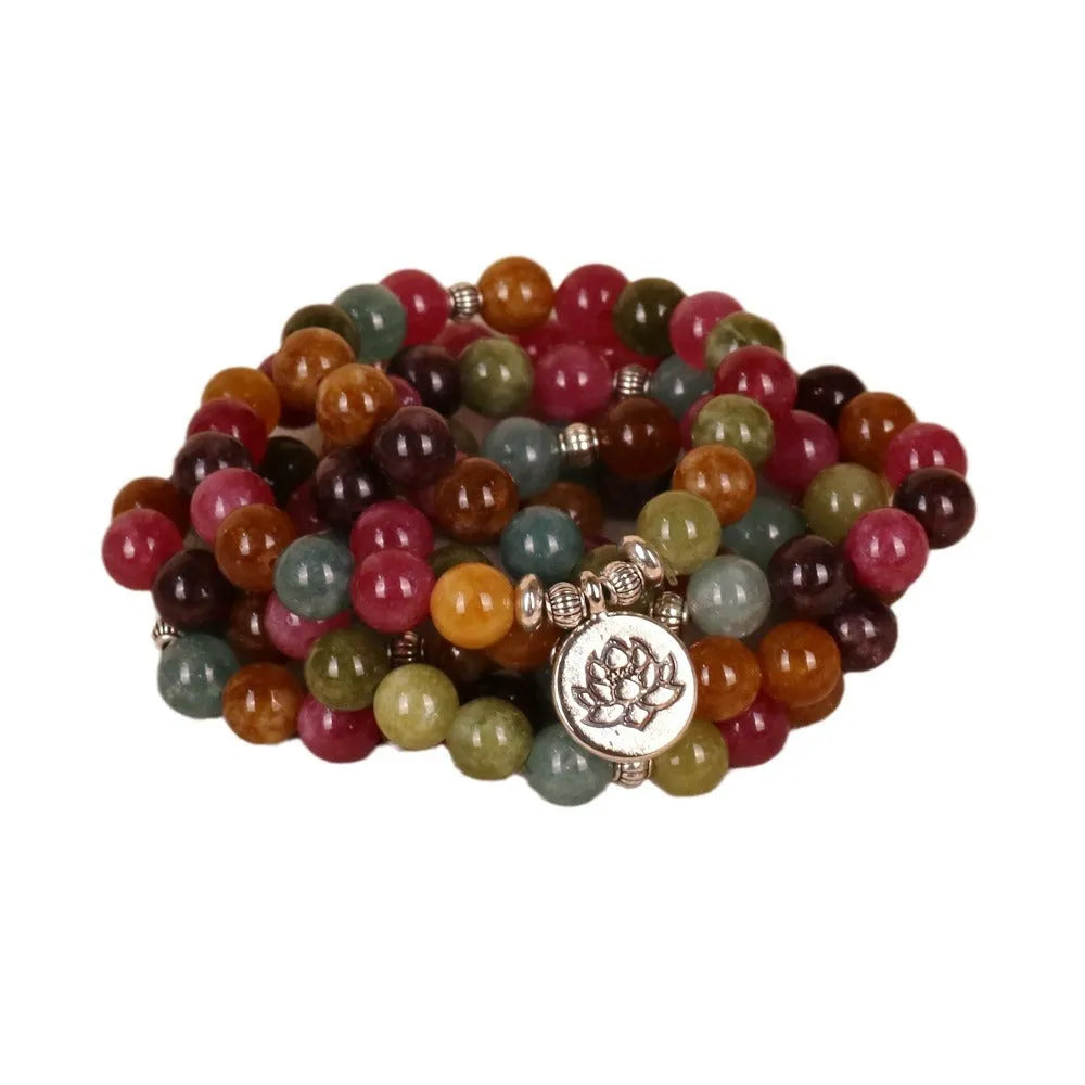 Close-up of a multi-layer beaded bracelet with 108 beads and a hanging lotus charm, made from alloy and tourmaline-coloured material.