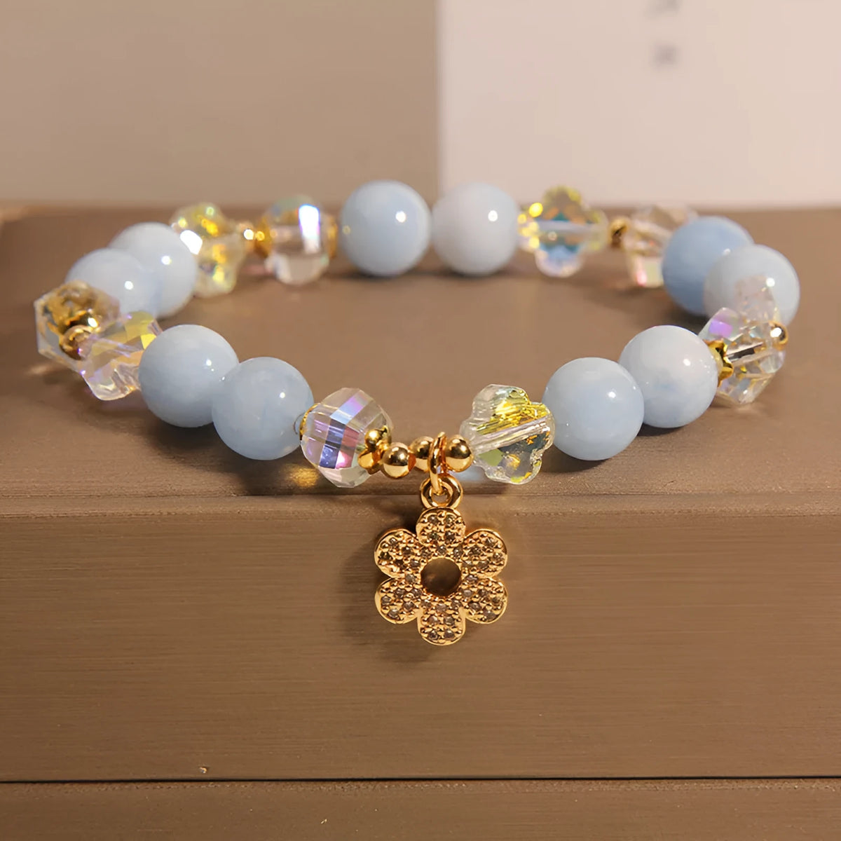 Aquamarine crystal bracelet with a four-leaf clover charm and a pearl decorative element on a wrist.