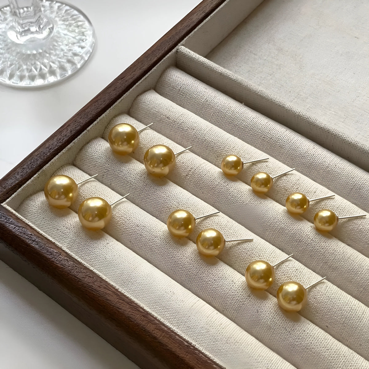 A pair of large geometric pearl stud earrings with an eight-point star detail on a silver setting.