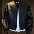 Man wearing a long black PU leather jacket with a tight, tailored fit.