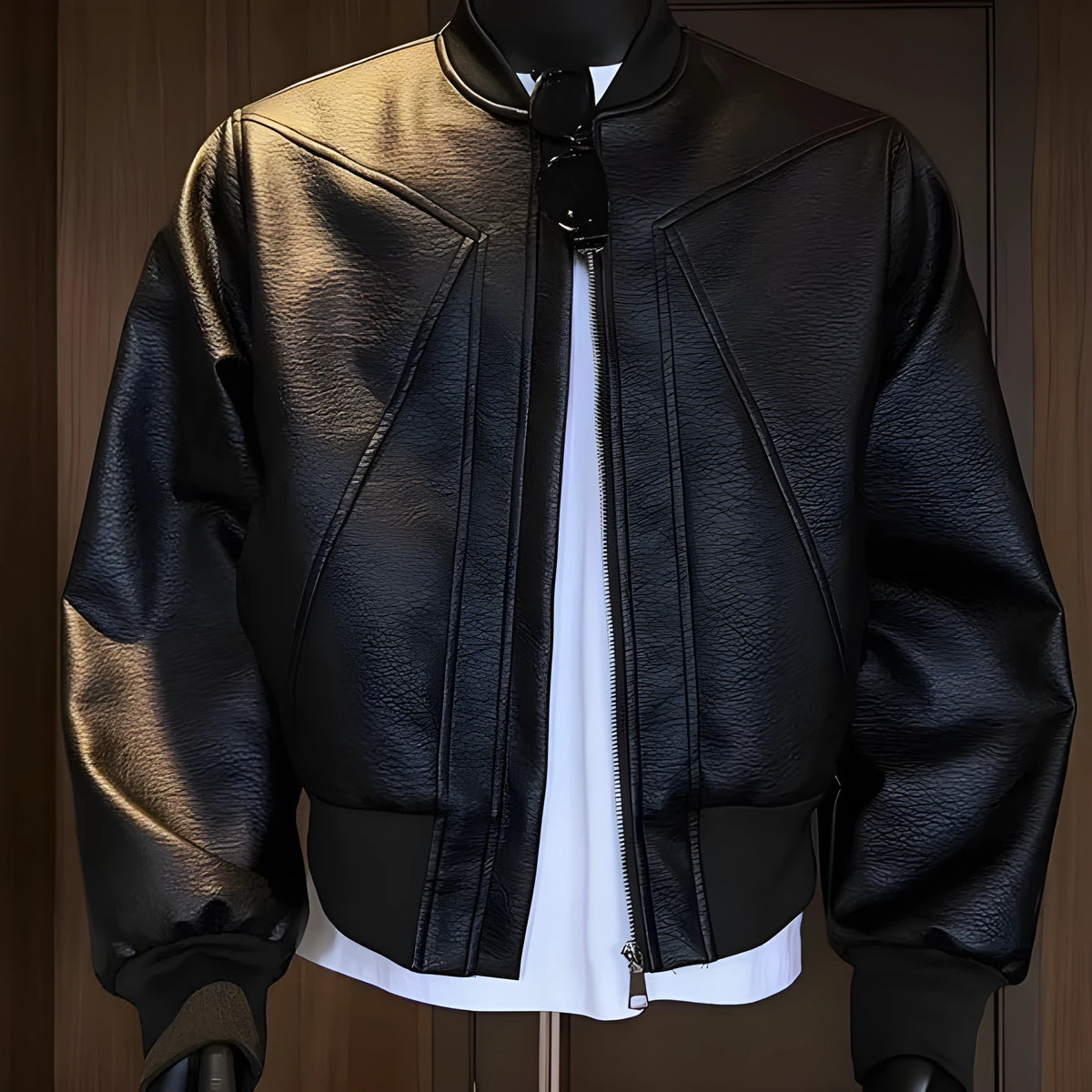 Man wearing a long black PU leather jacket with a tight, tailored fit.