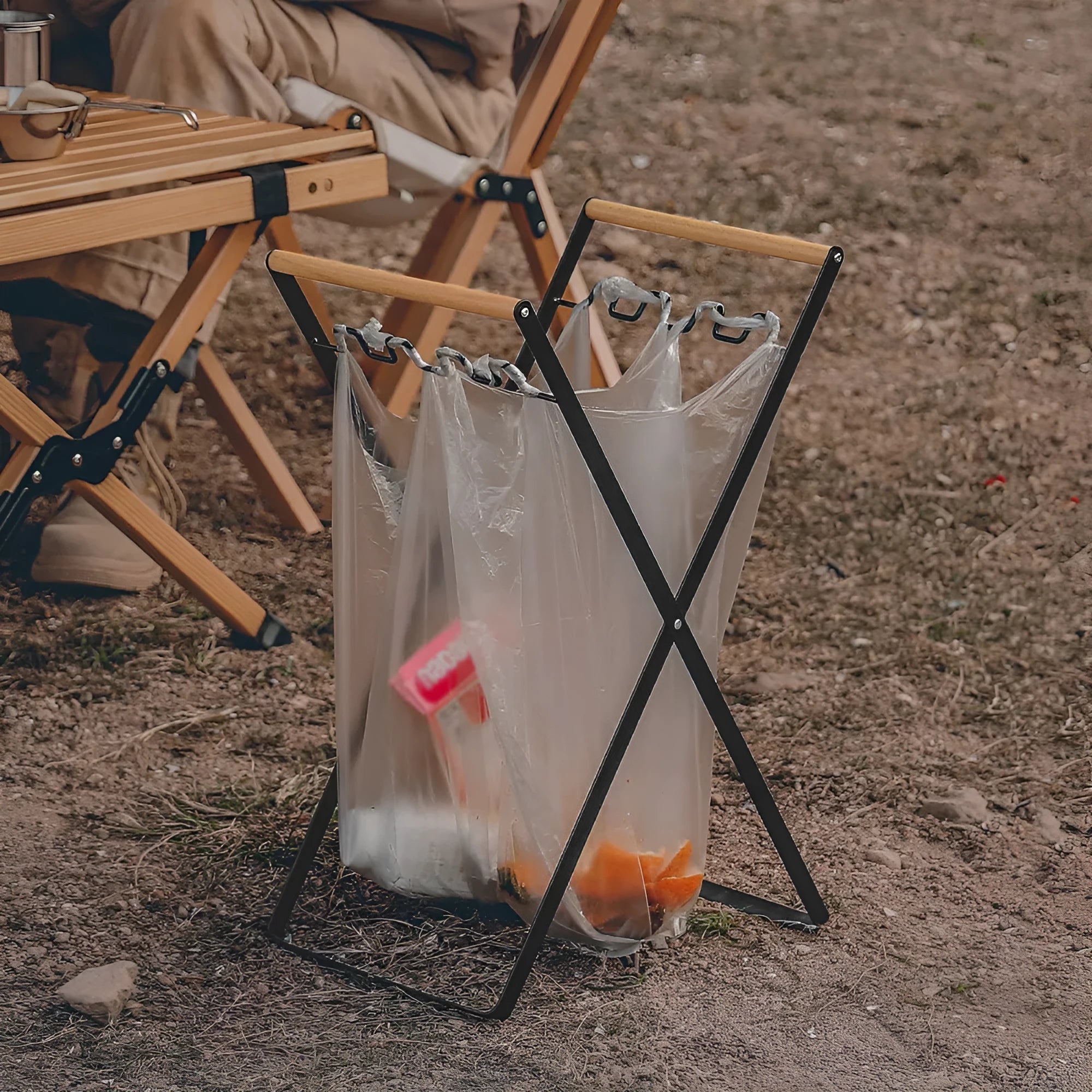 Black folding iron outdoor trash rack with a wooden handle holding a waste bag.