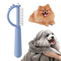 Blue dinosaur-shaped self-cleaning cat brush with stainless steel pins on a white background.
