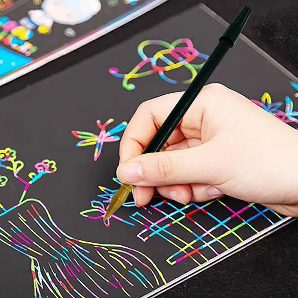 A white scratch pen tool for children's rainbow art and craft projects on a black surface.