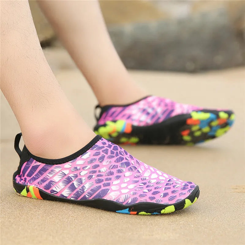 Pair of lycra and EVA water shoes in camouflage colour on a sandy beach