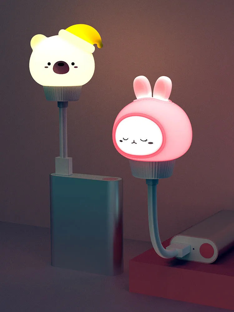 Cartoon animal USB night light with remote control on a bedside table.