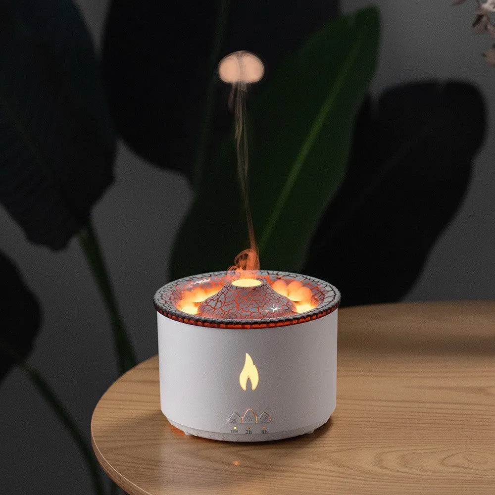 White and blue volcano-shaped tabletop humidifier emitting a mist, with mechanical controls and a UK plug adaptor.